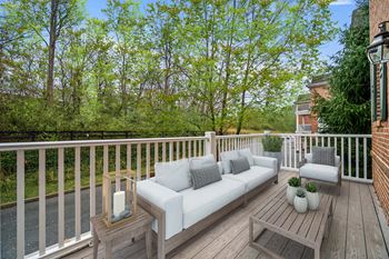 A wooden deck with a white couch and pillows.